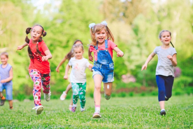 A group of children running on a grassy field.