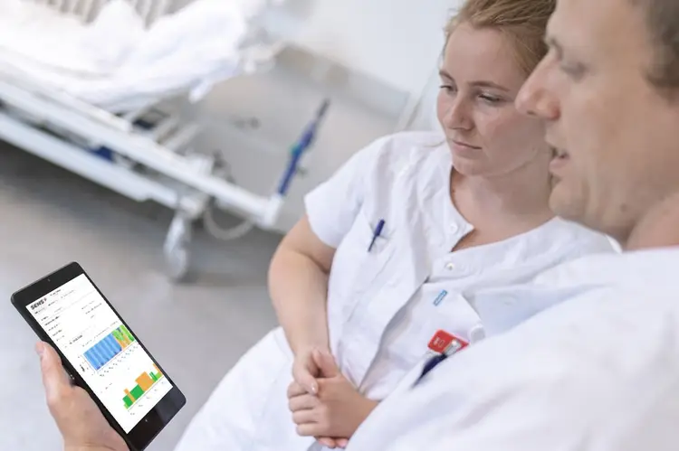 Two nurses looking at a tablet in a hospital.