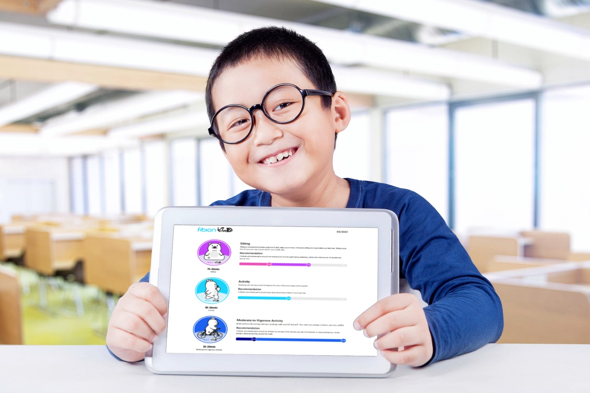 A smiling child with glasses holding a tablet displaying the Fibion Kids educational app in a classroom setting.