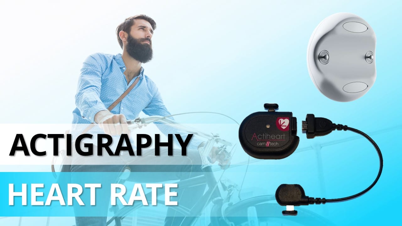 A bearded man rides a bicycle, highlighted by the text "Actigraphy" and "Heart Rate" beside images of health-monitoring devices. These include a wearable sensor and a compact device labeled "Actiheart," emphasizing the importance of comprehensive research in health monitoring.