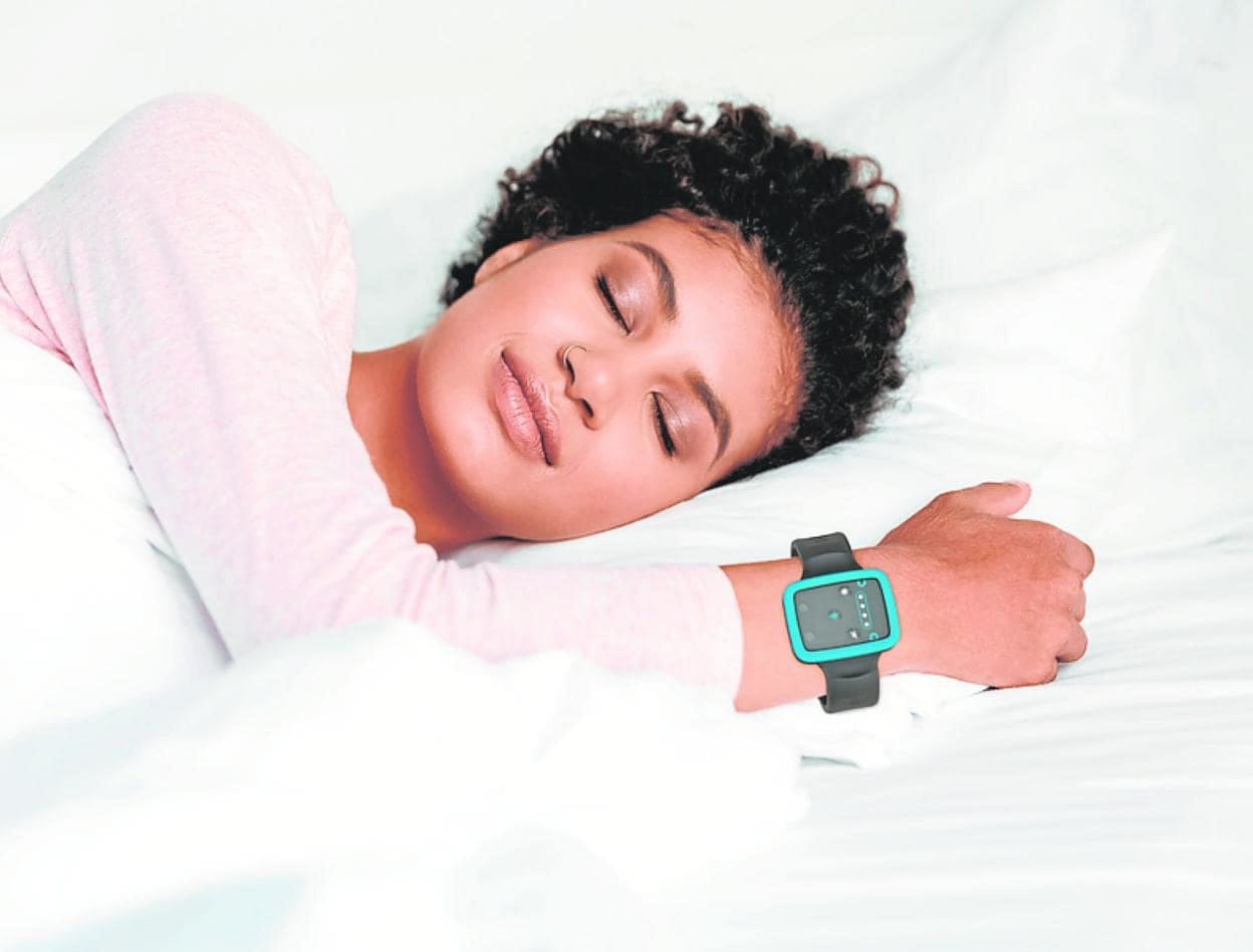 A person sleeps on their side in a bed, wearing a smartwatch on their wrist, utilizing Fibion Sleep Solutions for optimal night rest.