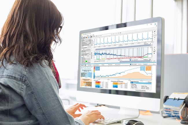 Person working on a computer with various graphs and charts displayed on the screen, utilizing SENS Motion for precise data analysis.