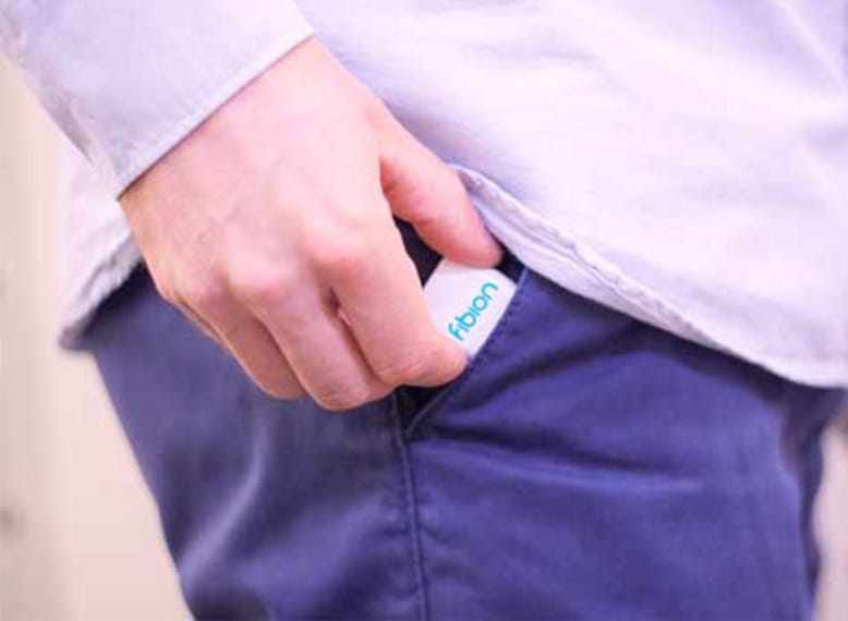 A person discreetly slips a small white object with blue text, much like concealing vital elements for their day, into their pants pocket.