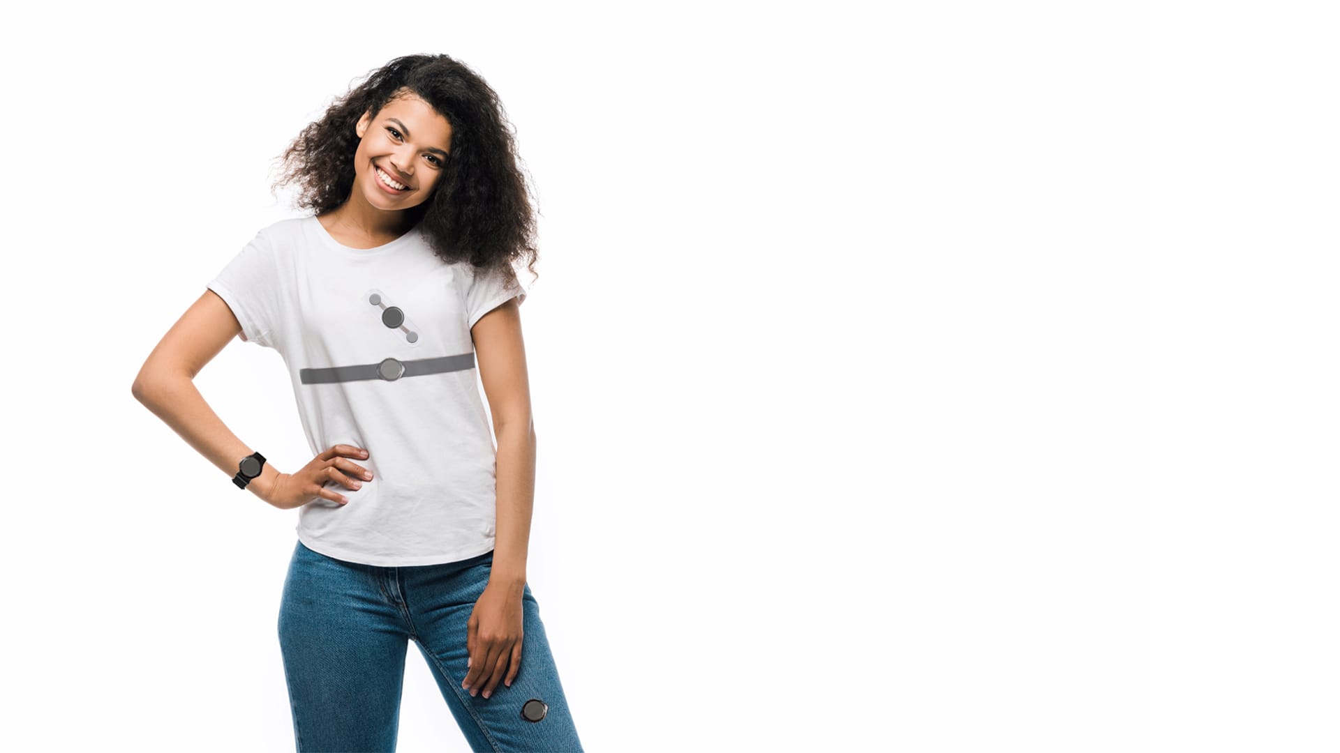 A person with curly hair smiles, wearing a stylish white t-shirt featuring a flash of gray abstract design and blue jeans, posing confidently with one hand on their hip against a crisp white background.