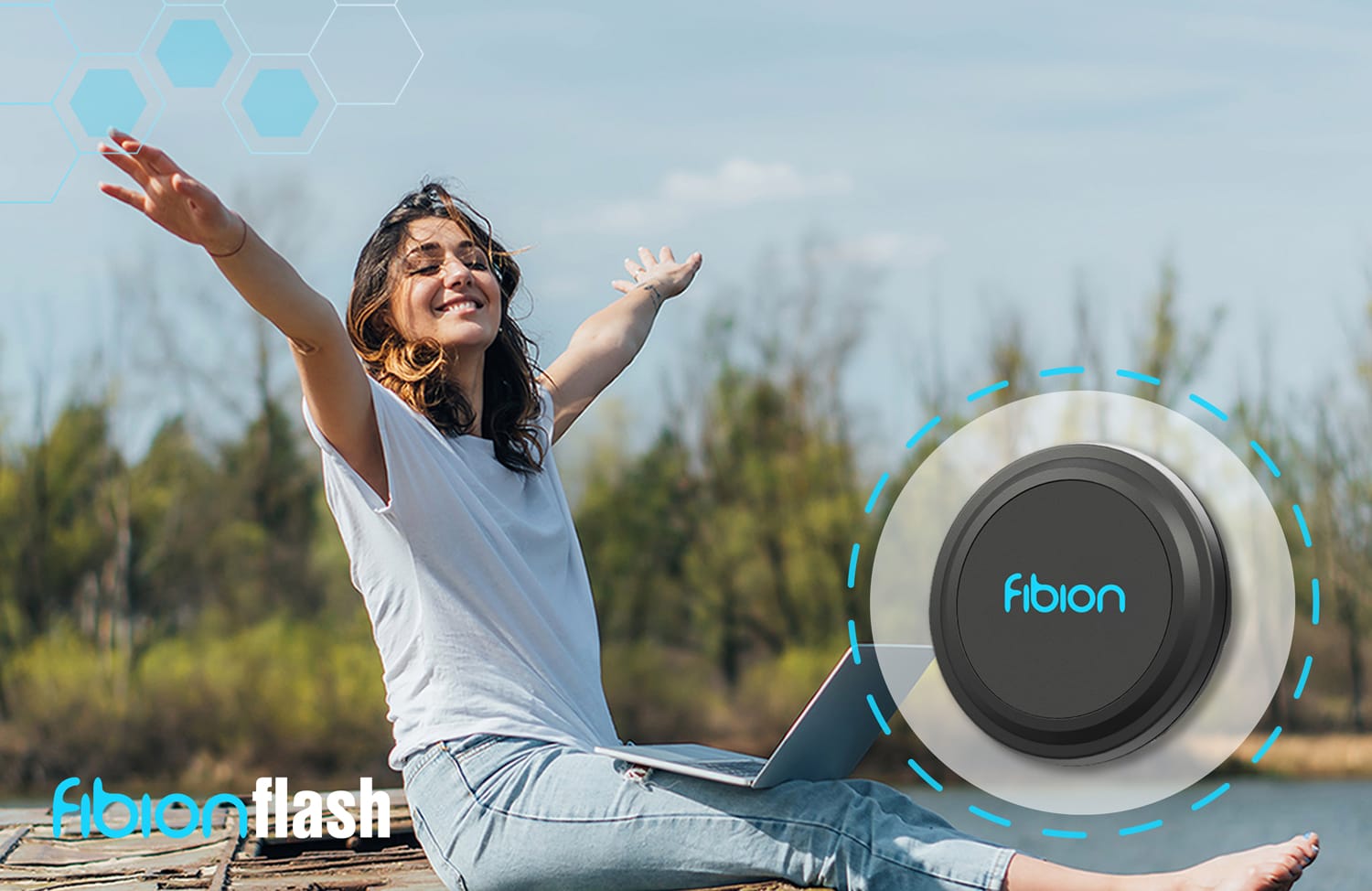 A woman sits on the grass with arms raised beside a Fibion Flash device, a small circular gadget designed for activity monitoring, in an outdoor setting.