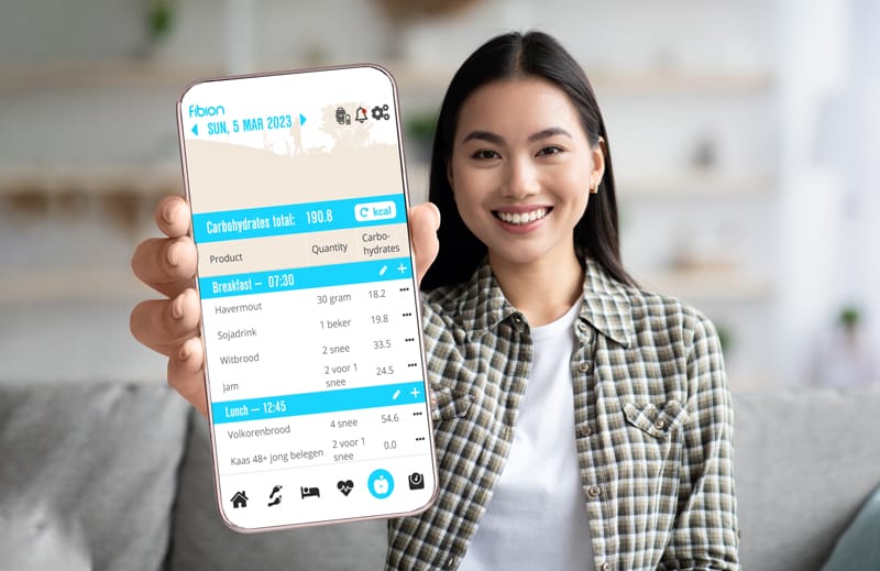 A person holds a phone showcasing a nutrition tracking app, enhanced by SENS Motion technology, revealing carbohydrate details for breakfast and lunch.