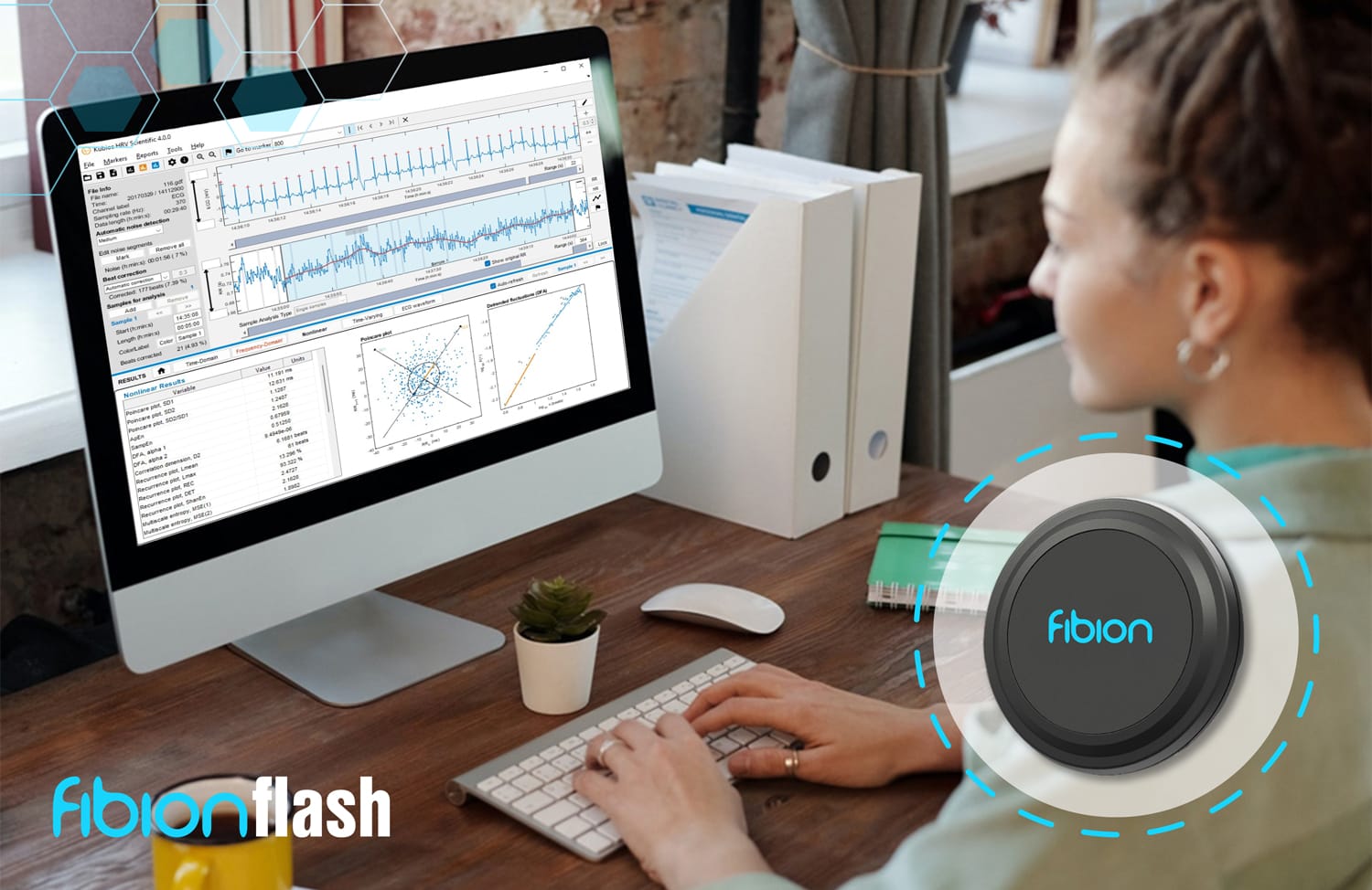 A person is seated at a desk, engrossed in analytics software on their computer. Nearby, the sleek Fibion Flash—a top-notch research sensor—adds a touch of tech-savvy sophistication to the setup.