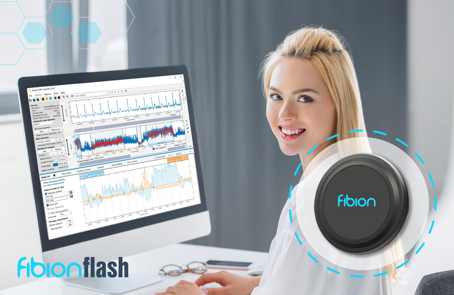 A person sitting at a desk smiles at the camera. A computer screen displays graphs and data, while an Android device runs a Free ECG Recorder App. In the foreground, a circular device with "fibion" branding is prominently featured.