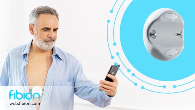 A man in a blue shirt uses a smartphone, possibly conducting research. A gadget for remote patient monitoring is displayed next to him. The image includes the text "fibion" and "web.fibion.com".