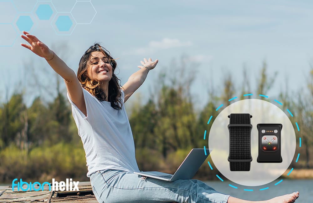 A woman sits outdoors with arms outstretched, embodying serenity next to an image of the SENS Motion wearable device. Surrounded by trees and sky, she exudes peaceful harmony with nature and technology.