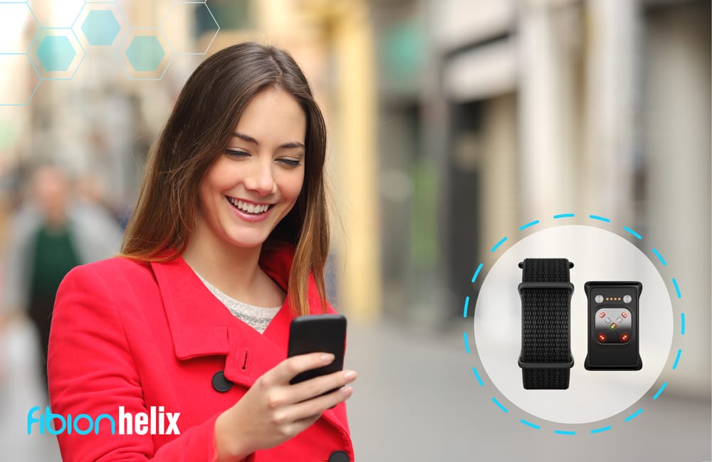 A smiling woman in a red coat holds a smartphone. To the right, a graphic of the SENS Motion wearable device with straps is shown, highlighting its sleek design. "Fibion Helix" text is visible in the bottom left corner, adding to the innovative appeal.