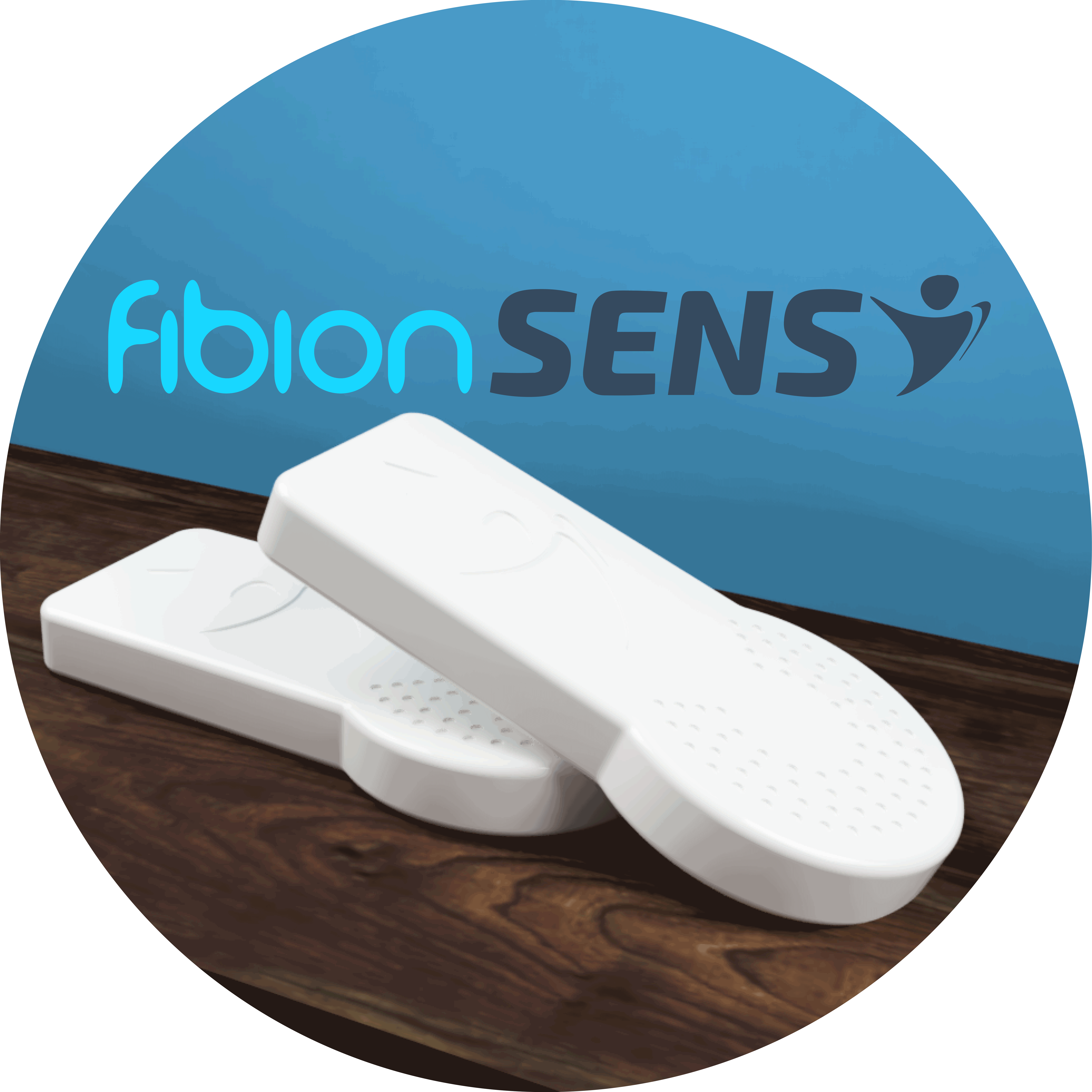 Two white rectangular devices with rounded edges rest on a wooden surface, while "Fibion SENS" is prominently displayed on a blue wall in the background, suggesting their use in long-term monitoring applications.