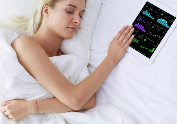 A woman sleeping in bed with an ipad in her hand.