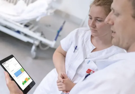 Two nurses looking at a tablet in a hospital.